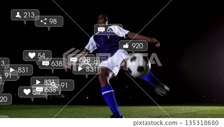 Kicking soccer player wearing purple jersey on pitch at night, with ball and floating social icons 135318680