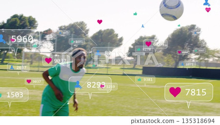 Running player wearing green-white kit chasing ball on grass pitch, showing floating social icons 135318694