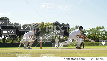 Swinging right-handed batsman driving ball on cricket pitch, with social media icons, copy space 135318702