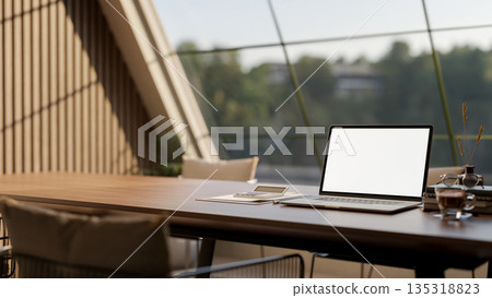 White screen laptop with coffee and calculator on wooden table and metal chair under roof window. 135318823