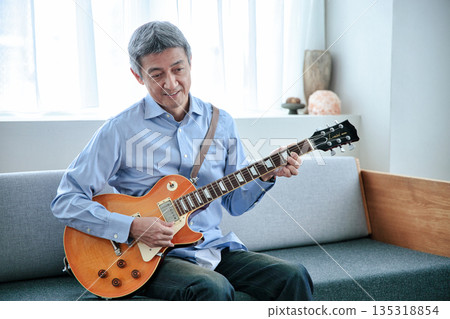 一位微笑的老人抱著一把電吉他 135318854
