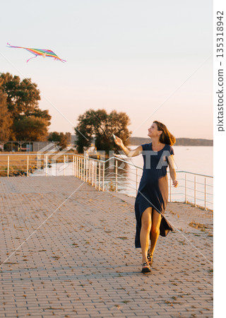 Joyful Pregnant Woman Playing With Kite Joyful Pregnant Woman Playing With Kite 135318942