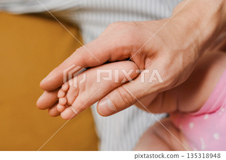 Father Holding Tiny Baby Foot In Gentle Hands Closeup Father Holding Tiny Baby Foot In Gentle Hands Closeup 135318948