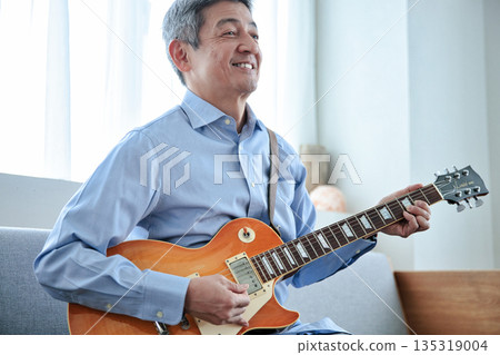 一位微笑的老人抱著一把電吉他 135319004