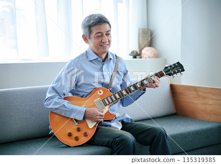 一位微笑的老人抱著一把電吉他 135319385