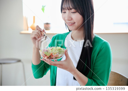 A young woman eating a salad 135319399
