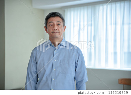 A smiling man in his 60s standing and looking at the camera 135319829
