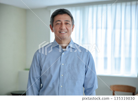 一位六十多歲的微笑的男子站著,看著鏡頭。 一位六十多歲的微笑的男子站著,看著鏡頭。 135319830