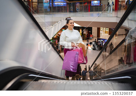 Shopping adventure unfolds as a woman descends the escalator Shopping adventure unfolds as a woman descends the escalator 135320037
