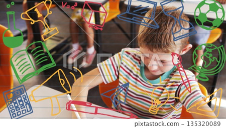 Schoolboy writing with pencil at desk in classroom, striped shirt, icons overlay, copy space Schoolboy writing with pencil at desk in classroom, striped shirt, icons overlay, copy space 135320089