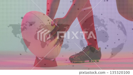 Aligning athlete wearing red socks, cleats positioning ball on tee in studio, map projection 135320100