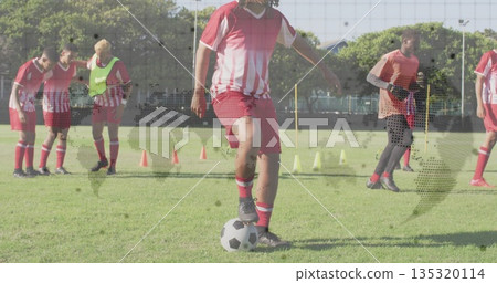 Central soccer player controlling ball in grass training pitch, with cones and bibs Central soccer player controlling ball in grass training pitch, with cones and bibs 135320114