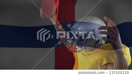 Helmeted yellow-jerseyed football player holding football in studio, flag overlay, copy space Helmeted yellow-jerseyed football player holding football in studio, flag overlay, copy space 135320120