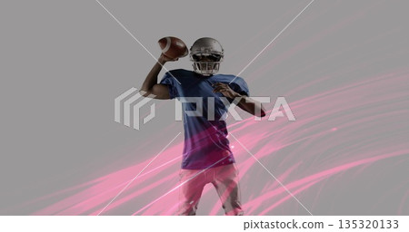 Holding football, preparing to pass in studio, quarterback wearing helmet with pink streak graphics 135320133
