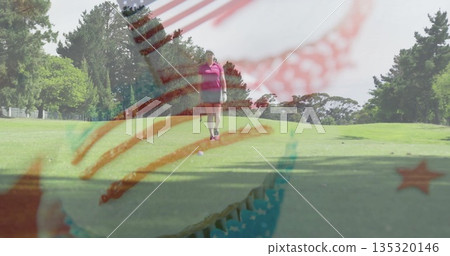Walking female golfer in pink polo, gray shorts across green fairway, with golf club, glove, ball Walking female golfer in pink polo, gray shorts across green fairway, with golf club, glove, ball 135320146