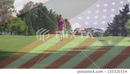 Walking female golfer wearing purple polo shirt and pink shorts on golf fairway, with golf ball Walking female golfer wearing purple polo shirt and pink shorts on golf fairway, with golf ball 135320154