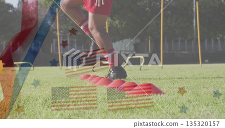 Stepping athlete wearing red shorts on field, with red cones, yellow hurdles and poles, copy space 135320157