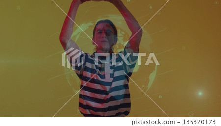 Raising arms above head creating curved shape at yellow backdrop, with holographic globe, UI icons 135320173