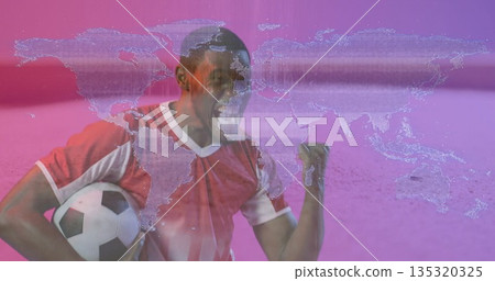 Shouting soccer player in red and white jersey gripping ball before pink backdrop with map overlay Shouting soccer player in red and white jersey gripping ball before pink backdrop with map overlay 135320325