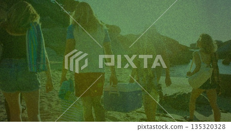 Walking five friends carrying coolers and towels on beach toward rocky shoreline, with straw hat Walking five friends carrying coolers and towels on beach toward rocky shoreline, with straw hat 135320328