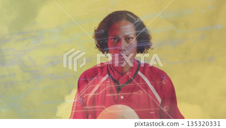 Holding female athlete wearing red jersey with white volleyball against yellow tech studio backdrop Holding female athlete wearing red jersey with white volleyball against yellow tech studio backdrop 135320331