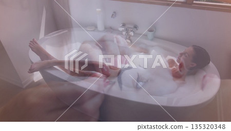 Reclining woman with hair pulled back soaking in bathtub in home bathroom, foam, smartphone overlay Reclining woman with hair pulled back soaking in bathtub in home bathroom, foam, smartphone overlay 135320348