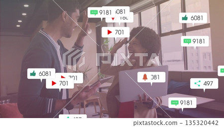 High-fiving colleagues in office lounge with tablet smartphone notification icon overlays High-fiving colleagues in office lounge with tablet smartphone notification icon overlays 135320442