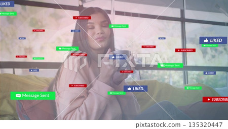 Cradling white mug, mid adult woman relaxing on sofa in home lounge, with floating UI icons 135320447