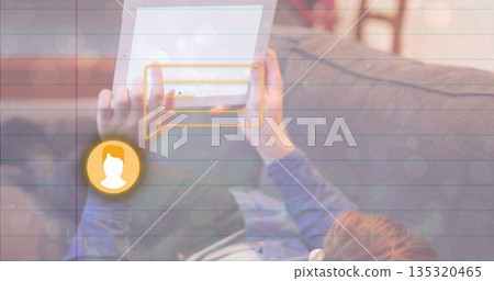 Reclining man tapping white tablet in home living room, with chat bubble and avatar icon graphic 135320465