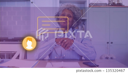 Senior medical professional consulting virtually in home kitchen, with stethoscope and chat icons 135320467