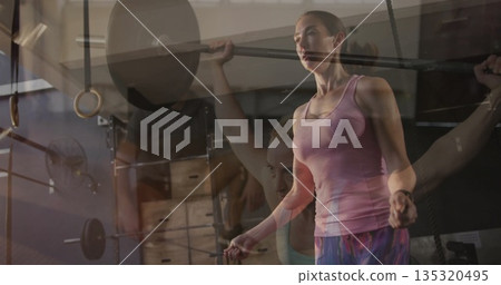 Lifting woman wearing pink tank top, holding barbell overhead at gym, with spotter, copy space Lifting woman wearing pink tank top, holding barbell overhead at gym, with spotter, copy space 135320495