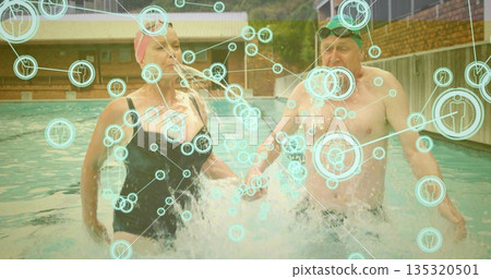 Walking couple in swim caps with goggles splashing water in outdoor pool, digital overlay graphics Walking couple in swim caps with goggles splashing water in outdoor pool, digital overlay graphics 135320501