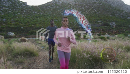 Jogging couple moving along dirt trail with grass, boulders and floating digital overlays 135320510