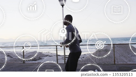 Jogging man wearing sportswear and earphones moving along seaside promenade, with analytics icons Jogging man wearing sportswear and earphones moving along seaside promenade, with analytics icons 135320513