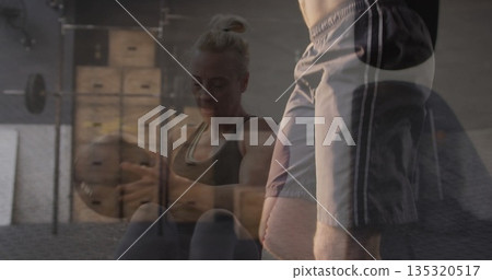 Performing weighted sit-ups woman wearing sportswear holding medicine ball on gym mat by plyo boxes 135320517