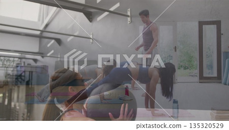 Five participants wearing sportswear planking while following instructor in studio, with yoga mats Five participants wearing sportswear planking while following instructor in studio, with yoga mats 135320529