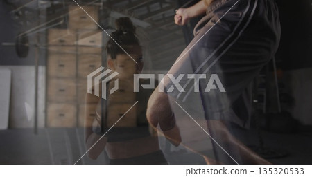 Delivering punches and kicks boxer and trainer sparring in boxing gym, with gloves and plyo boxes Delivering punches and kicks boxer and trainer sparring in boxing gym, with gloves and plyo boxes 135320533