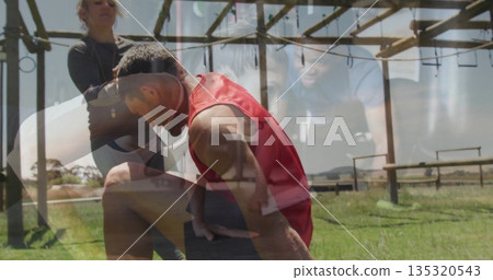 Kneeling man in sportswear receiving support from woman at park obstacle course with wooden frame 135320543