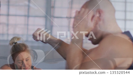 Punching shirtless man training boxing with partners in studio, with grid windows, white headset Punching shirtless man training boxing with partners in studio, with grid windows, white headset 135320544