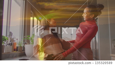 Arranging bottles and plants on countertop in kitchen by window and cabinets, mother and daughter Arranging bottles and plants on countertop in kitchen by window and cabinets, mother and daughter 135320589