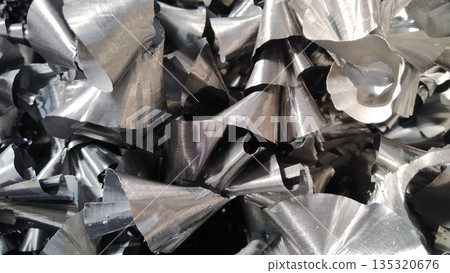 Steel scrap materials recycling. Aluminum chip waste after machining metal parts on a cnc lathe. Closeup twisted spiral steel shavings. Small roughness sharpness, Steel scrap materials recycling. Aluminum chip waste after machining metal parts on a cnc lathe. Closeup twisted spiral steel shavings. Small roughness sharpness, 135320676