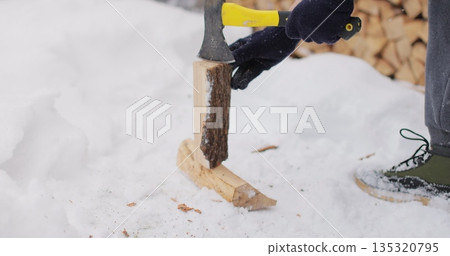 Man is chopping firewood in the backyard of his house. Preparations for cold winter months. Man is chopping firewood in the backyard of his house. Preparations for cold winter months. 135320795