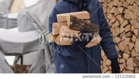 Man takes logs from a woodcutter in his hands for heating in the house. 135320802