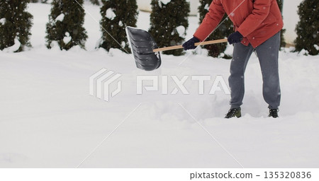 Young man cleans snow with a shovel after snowfall background of the house in winter. Young man cleans snow with a shovel after snowfall background of the house in winter. 135320836