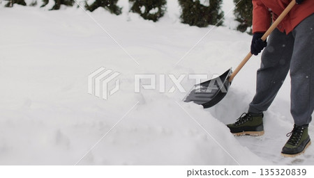 Male clean path near house. Person shoveling snow out of the driveway. Aftermath of a blizzard. Male clean path near house. Person shoveling snow out of the driveway. Aftermath of a blizzard. 135320839