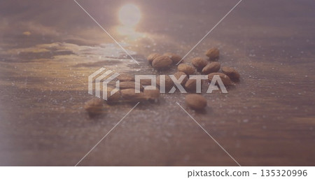Shimmering raw almonds resting on polished wooden tabletop, with sugar-like granules Shimmering raw almonds resting on polished wooden tabletop, with sugar-like granules 135320996