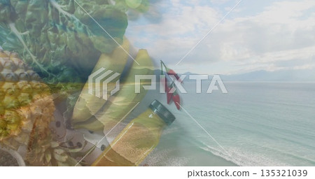 Blending pineapple, bananas, leafy greens, chili peppers and oil bottle over ocean beach scene Blending pineapple, bananas, leafy greens, chili peppers and oil bottle over ocean beach scene 135321039