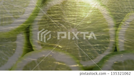 Glowing central lime slice revealing pale green flesh in still life, with sunlit water ripples Glowing central lime slice revealing pale green flesh in still life, with sunlit water ripples 135321062