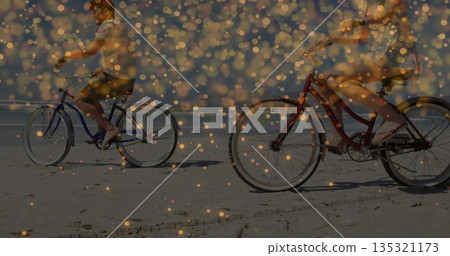 Riding couple pedaling red and blue cruiser bicycles on sandy shoreline, with golden light overlay Riding couple pedaling red and blue cruiser bicycles on sandy shoreline, with golden light overlay 135321173