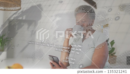 Holding smartphone and coffee mug, woman analyzing world map projection in home kitchen with plants Holding smartphone and coffee mug, woman analyzing world map projection in home kitchen with plants 135321241